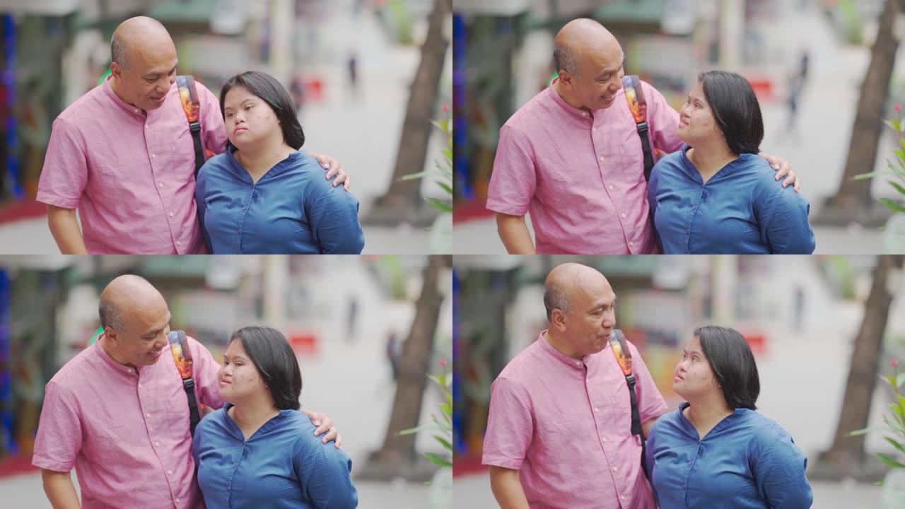 亚洲马来人退休父亲和他的唐氏综合症女儿在周末的结合时间在城市街道上聊天