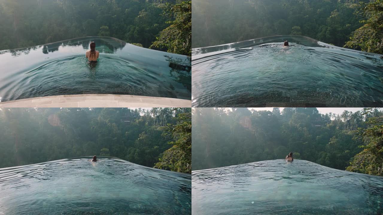 性感的女人在无边泳池游泳，享受异国情调的暑假在酒店水疗中心享受奢华的生活方式，可以看到热带丛林