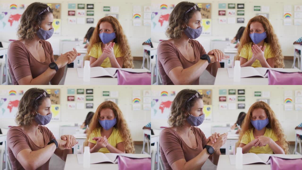 女教师和女孩戴着口罩在学校消毒双手