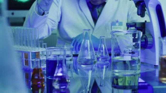 实验室科学家使用滴管或移液管和玻璃烧杯在紫外线实验室中测试化学反应。生物化学家病理学家实验的特写，医