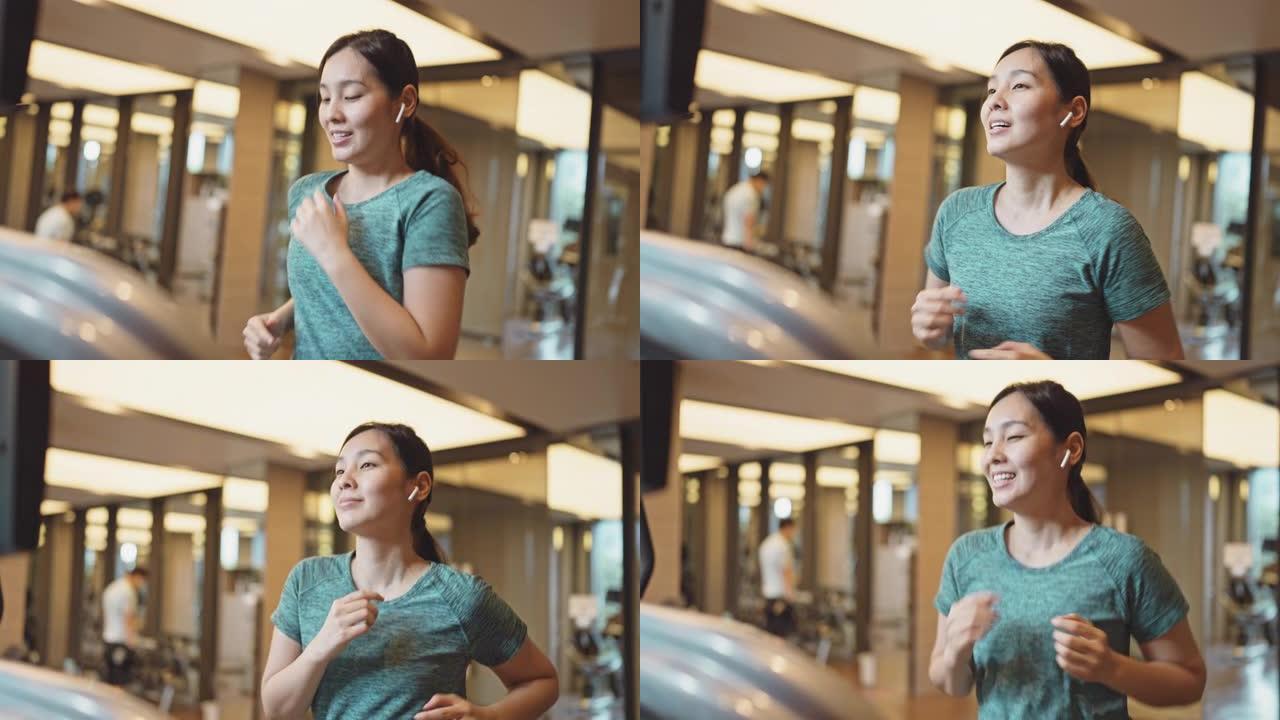 在健身房的跑步机上跑步的亚洲女性
