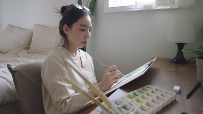 快乐的亚洲女人在家画画。