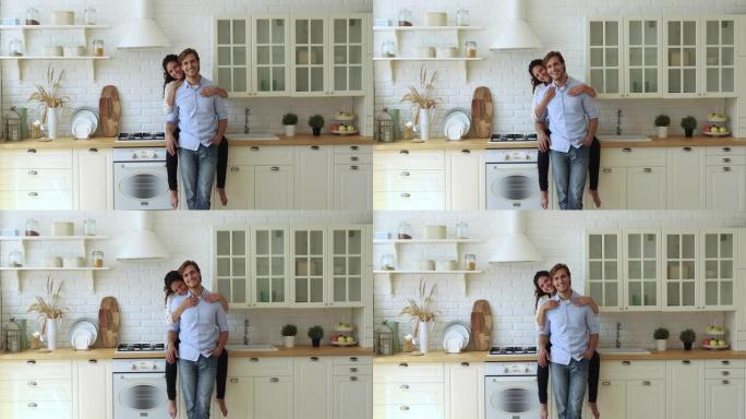 妻子坐在厨房台面上拥抱丈夫看着相机