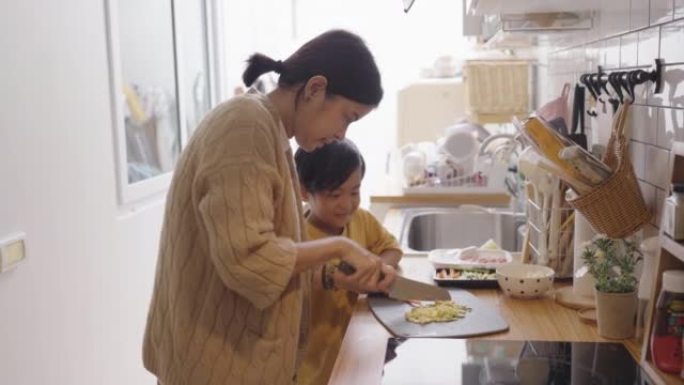 母亲和男孩在家在厨房做饭