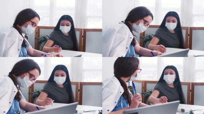 年轻的高加索医生妇女咨询戴口罩的混合种族病人妇女，在体检时拿着药瓶。