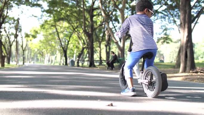 非裔美国男孩骑着自行车，在公园里回头看镜头