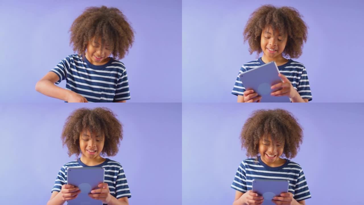 微笑男孩拿着数字平板电脑对着紫色工作室背景的工作室镜头 -- 慢动作镜头