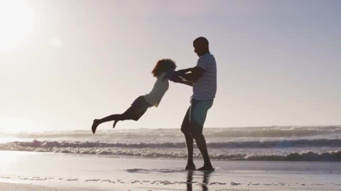 非裔美国父亲和他的女儿在海滩上玩耍