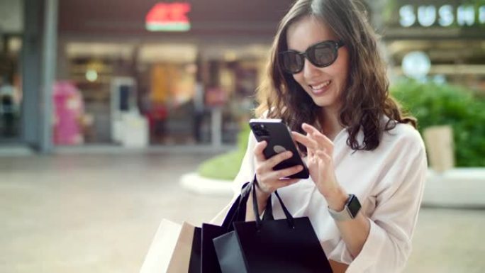 女人在购物中心购物，同时发短信和看零售展示