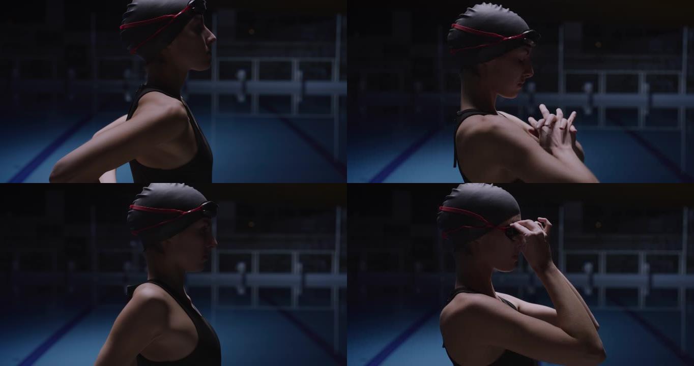 年轻的职业女游泳者戴着帽子和护目镜的电影镜头正在进行热身运动，同时准备在游泳池训练。运动、竞争、胜利