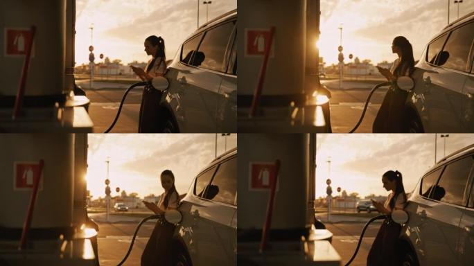 日落时加满汽车油箱的SLO MO年轻女子在电话中