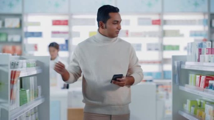 药房药店: 一个英俊的年轻印度男子使用智能手机设备的肖像，选择购买最好的药物，药物，维生素。货架上摆