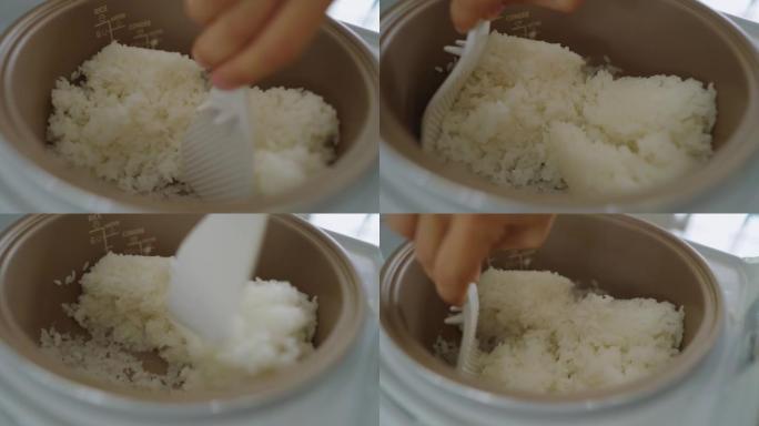 B-面目全非的女人在电饭锅中将米饭和塑料勺子混合