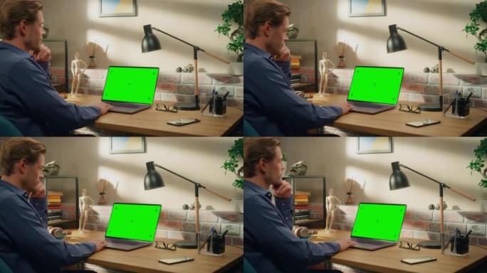 年轻英俊的男人在家工作，手提电脑上有绿屏模拟显示。创意男性查看社交媒体，浏览互联网。阁楼城市公寓的客