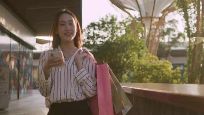 亚洲女子在商场里背着购物袋散步