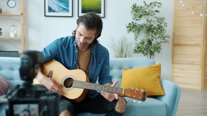 年轻音乐家视频记录器为互联网音乐博客录制视频弹吉他和使用相机交谈