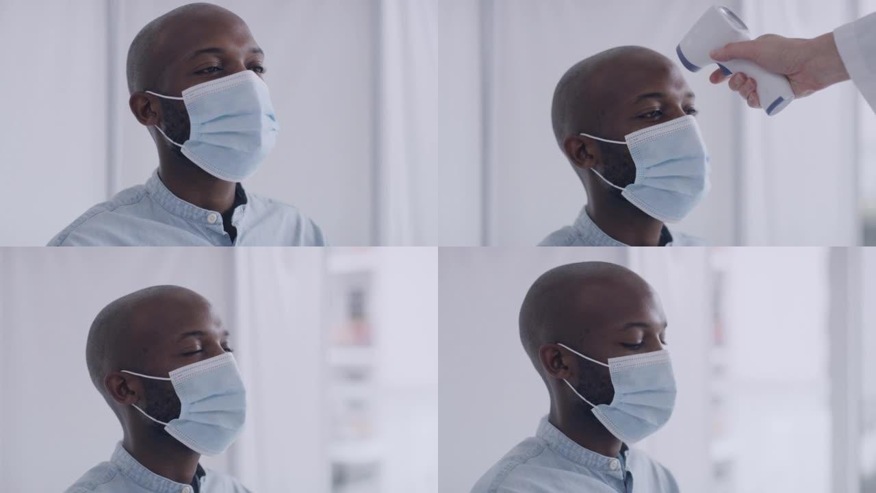 在大流行期间，一名男子戴着口罩在医疗机构由医护人员测量体温。在病毒爆发期间，年轻男性被单独隔离。