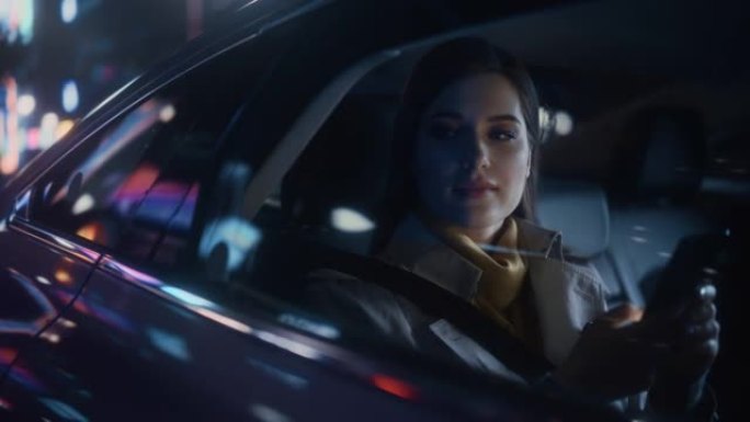 时尚的女性晚上坐出租车后座回家。美丽的女人乘客使用智能手机，在城市街道上开着霓虹灯的汽车时看着窗外。