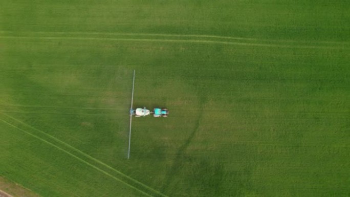 空中，自上而下: 蓝色拖拉机，配有现代化的农用设备，为农田施肥