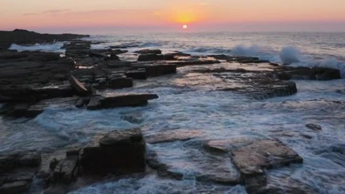 南非东开普省姆坎巴蒂自然保护区崎rock不平的岩石海滩海岸线上的夕阳和海浪的鸟瞰图