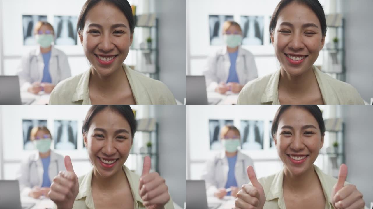 自信的亚洲女医生和年轻的病人女孩在诊所或医院的办公桌上做着竖起大拇指，微笑着看着相机。
