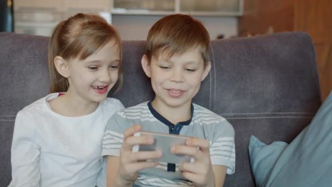 儿童兄弟姐妹在智能手机上玩电子游戏并在家聊天