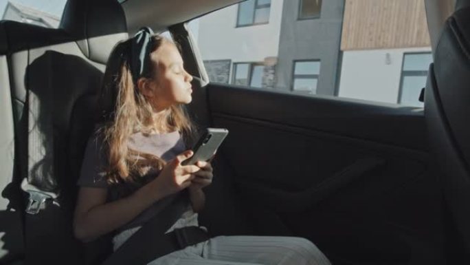 带手机的孩子坐在汽车后座上