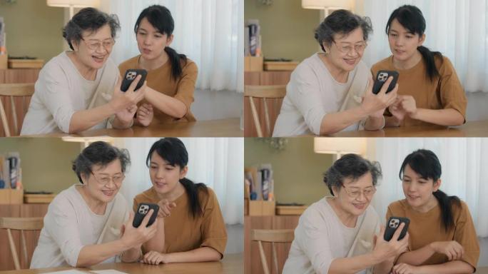 年轻的亚洲女性正在教她的母亲如何使用智能手机。