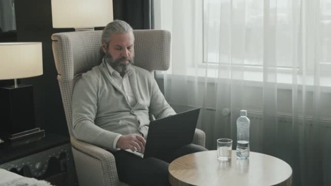 在酒店房间里使用笔记本电脑的商人