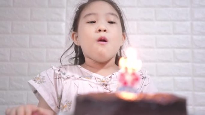 快乐的小女孩在生日蛋糕上吹蜡烛