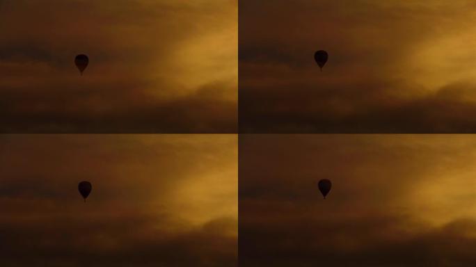 映影的热气球漂浮在多云的日落天空中