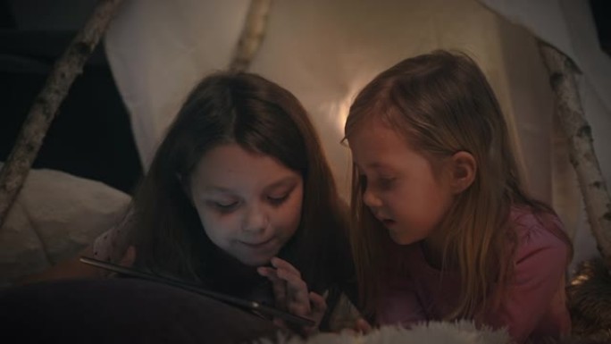 两个小女孩在帐篷里使用数字平板电脑