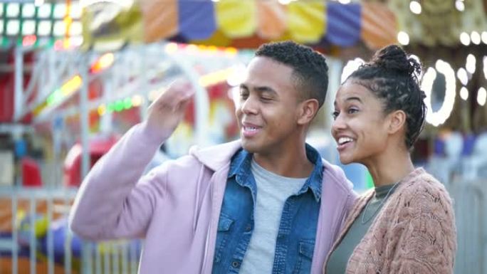 年轻的黑人夫妇在游乐园里微笑着挥手