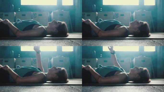 侧视图年轻漂亮的健康女人躺在筋疲力尽，检查智能手表应用程序在激烈的健身房锻炼后呼吸沉重。