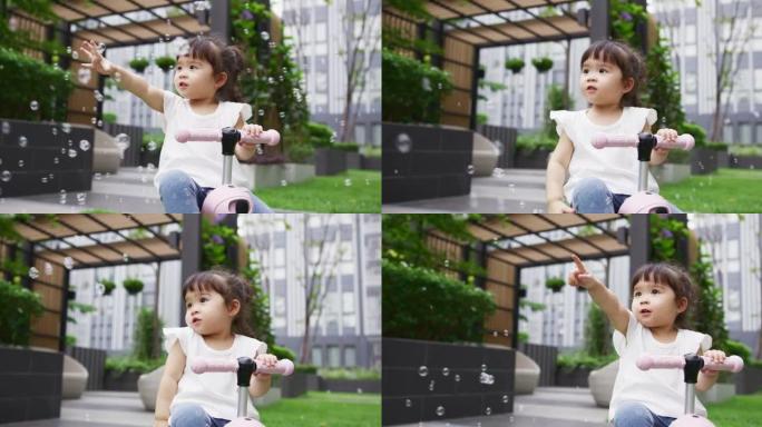 年轻的蹒跚学步的女孩在公园里玩泡泡