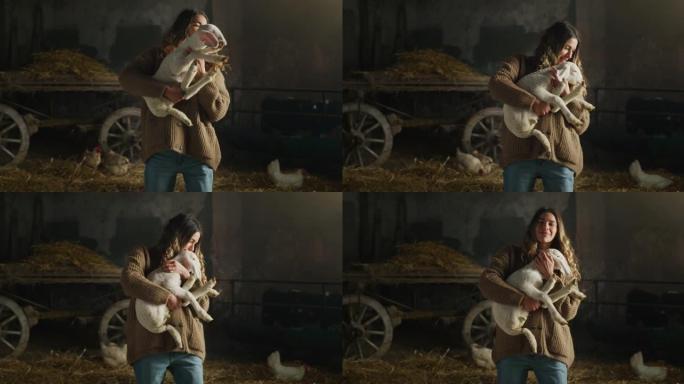 快乐的年轻女农场主的电影镜头是用爱和关怀爱抚生态生长的新生羔羊，用于农村农业农场干草仓的生物真正的羊