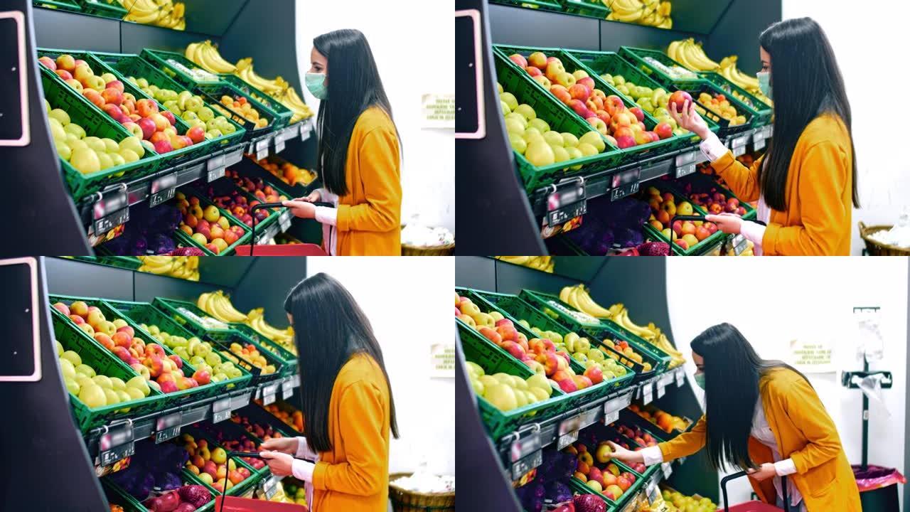 戴着口罩的SLO MO女人在杂货店的摊位上采摘苹果