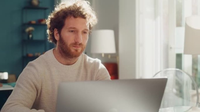 英俊的成年男子，姜黄色卷发，使用笔记本电脑，坐在公寓的客厅。敬业的人在家工作，在线购物，看视频或写电