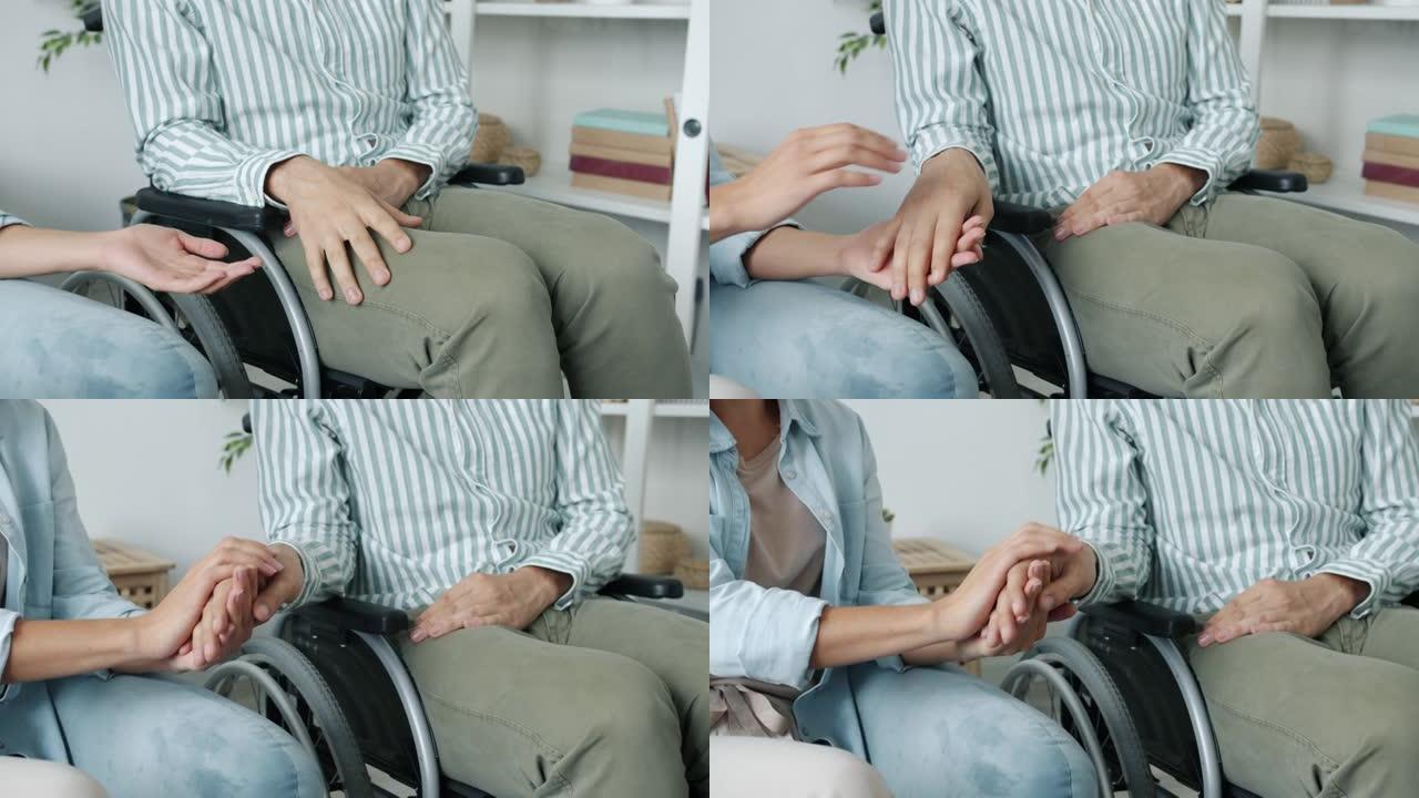 轮椅上的残障男子握着女人的手表达爱与支持的特写