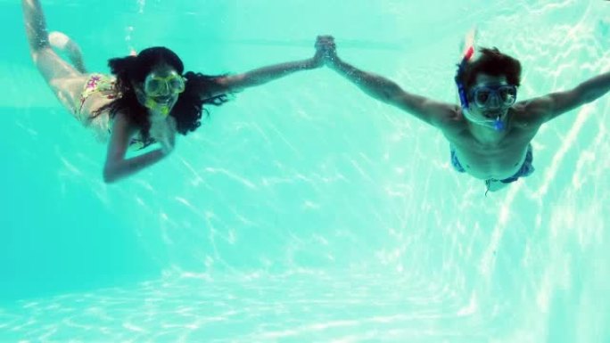 幸福的夫妇一起穿着通气管跳进游泳池