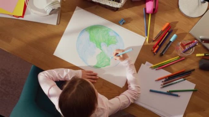 俯视图: 小女孩画我们美丽的地球。非常有才华的孩子在家里玩得开心，想象我们的家乡星球是一个快乐的地方