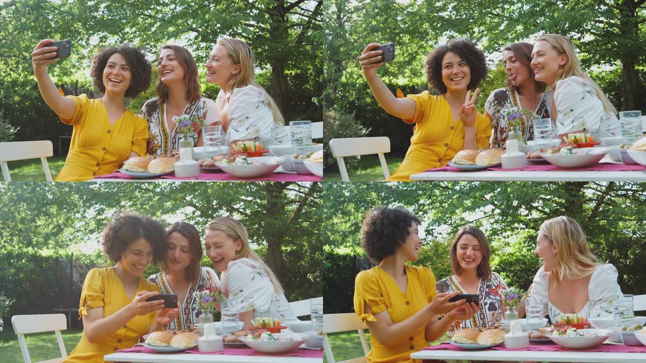 坐在户外花园里在家一起吃饭的女人在手机上摆姿势自拍 -- 慢动作拍摄