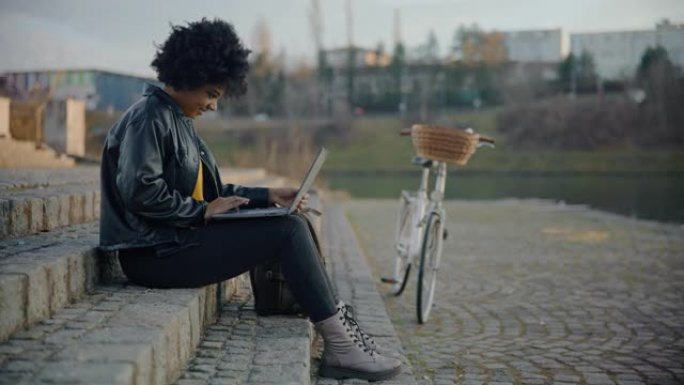 DS年轻的黑人妇女在城市郊区的某个地方使用笔记本电脑