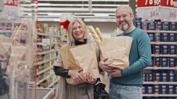 超市里拿着纸袋的成熟夫妇的肖像