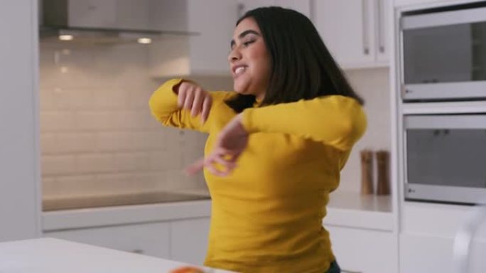 4k视频片段，一名年轻女子在家里的厨房里跳舞