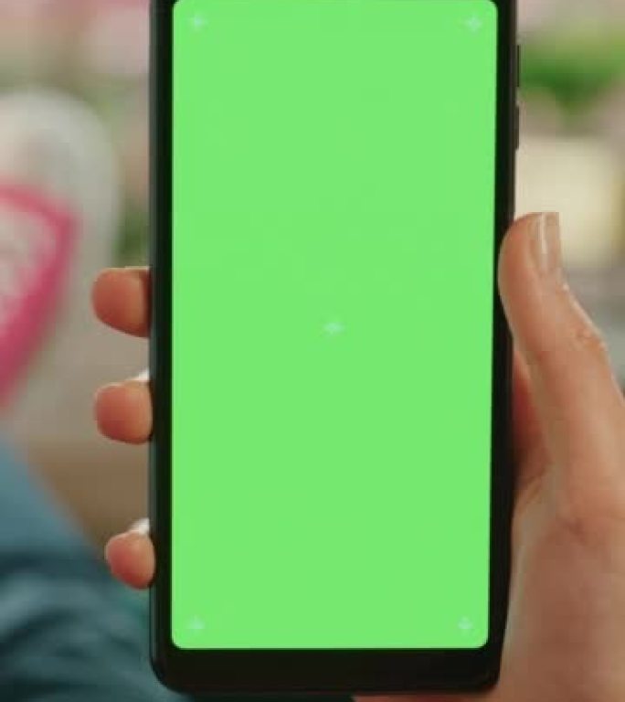 垂直屏幕: 女性手握智能手机，绿屏模拟显示。女性在家休息，并在移动设备上查看社交媒体。特写镜头。
