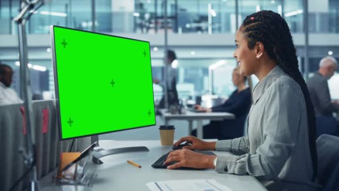 多样化的公司办公室: 美丽的黑人女性信息技术人员使用带有绿色色度键屏幕的台式计算机。创意软件工程师从