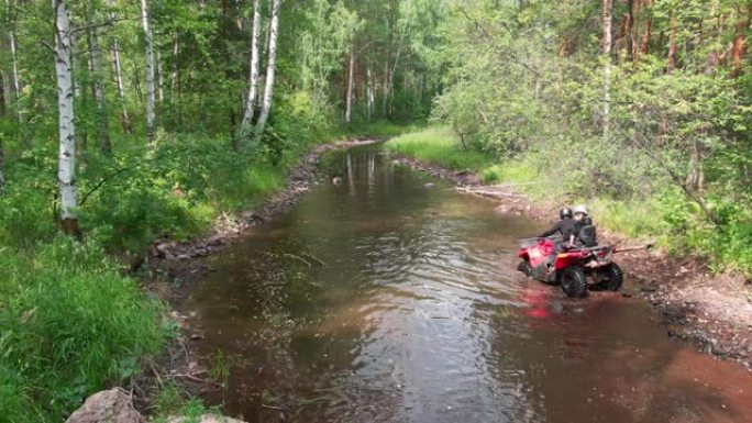 无人机拍摄了四轮摩托在河上行驶的情侣