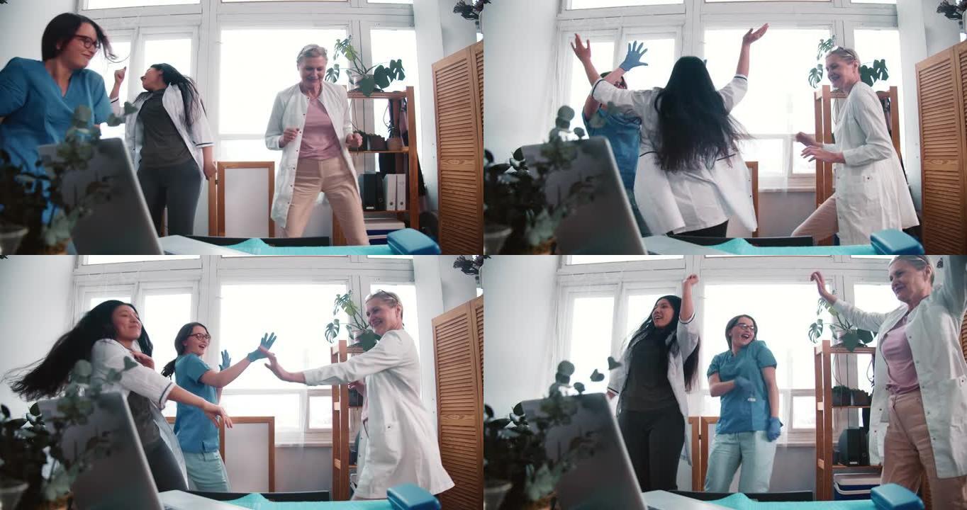 三个有趣的快乐的多民族女医生在工作实验室一起跳舞，庆祝战胜冠状病毒大流行。