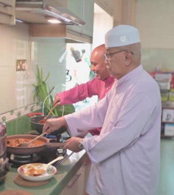 马来家庭祖父和父亲在厨房里并排烹饪传统食物咖喱，为哈里拉雅家庭团圆饭做准备